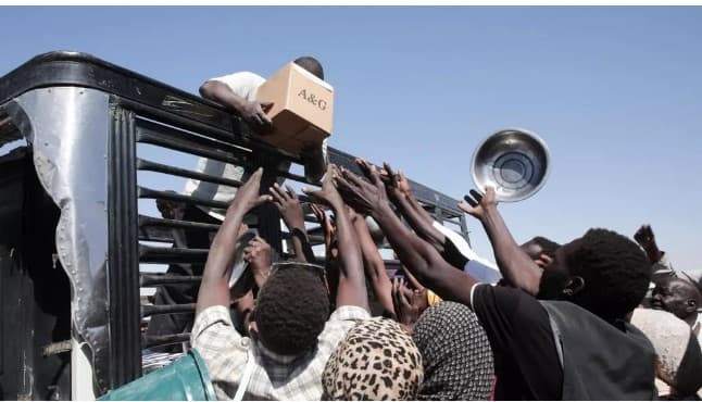 عائلات سودانية نازحة من الفاشر تتواصل مع عمال الإغاثة الذين يوزعون الإمدادات الغذائية في مخيم العفاد الذي تم إنشاؤه حديثاً في الضبعة، بولاية شمال السودان، الأحد 16 نوفمبر 2025. © أسوشييتد برس