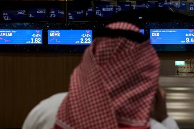متداول يقف أمام شاشات تعرض بيانات أسهم سوق دبي المالي في دبي يوم 30 ديسمبر 2025. رويترز